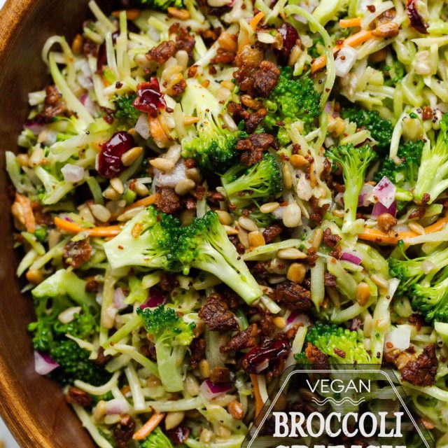 Vegan broccoli slaw salad in a wooden serving bowl sitting on a marble countertop.